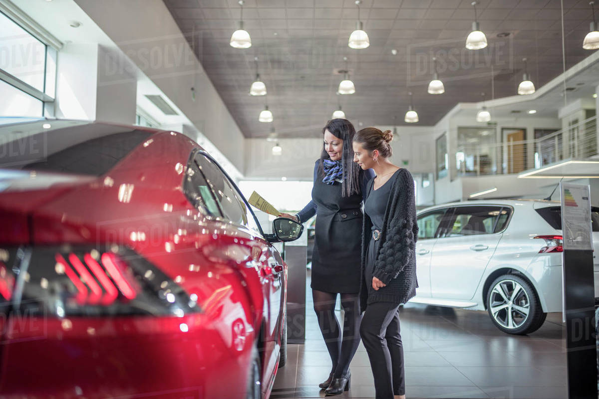 Saleswoman and customer inspecting new car in car showroom Royalty-free stock photo