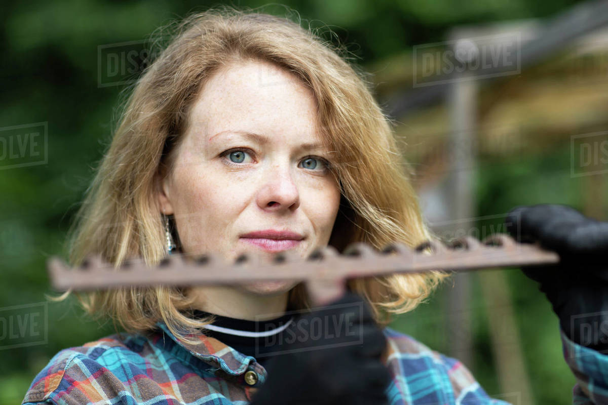 Mid adult woman holding garden rake, head and shoulder portrait Royalty-free stock photo