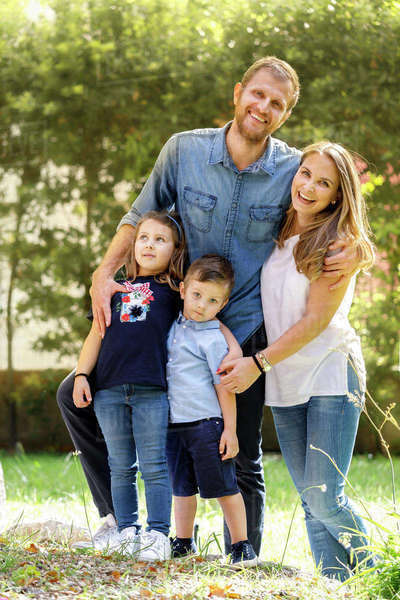 Family portrait, man and woman standing outdoors with boy and girl ...