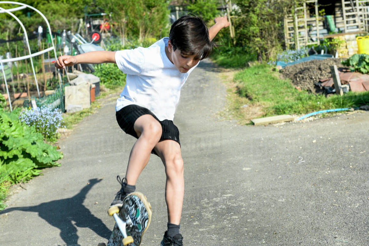 Boy with brown hair wearing t[shirt and shorts performing skateboard trick. Royalty-free stock photo