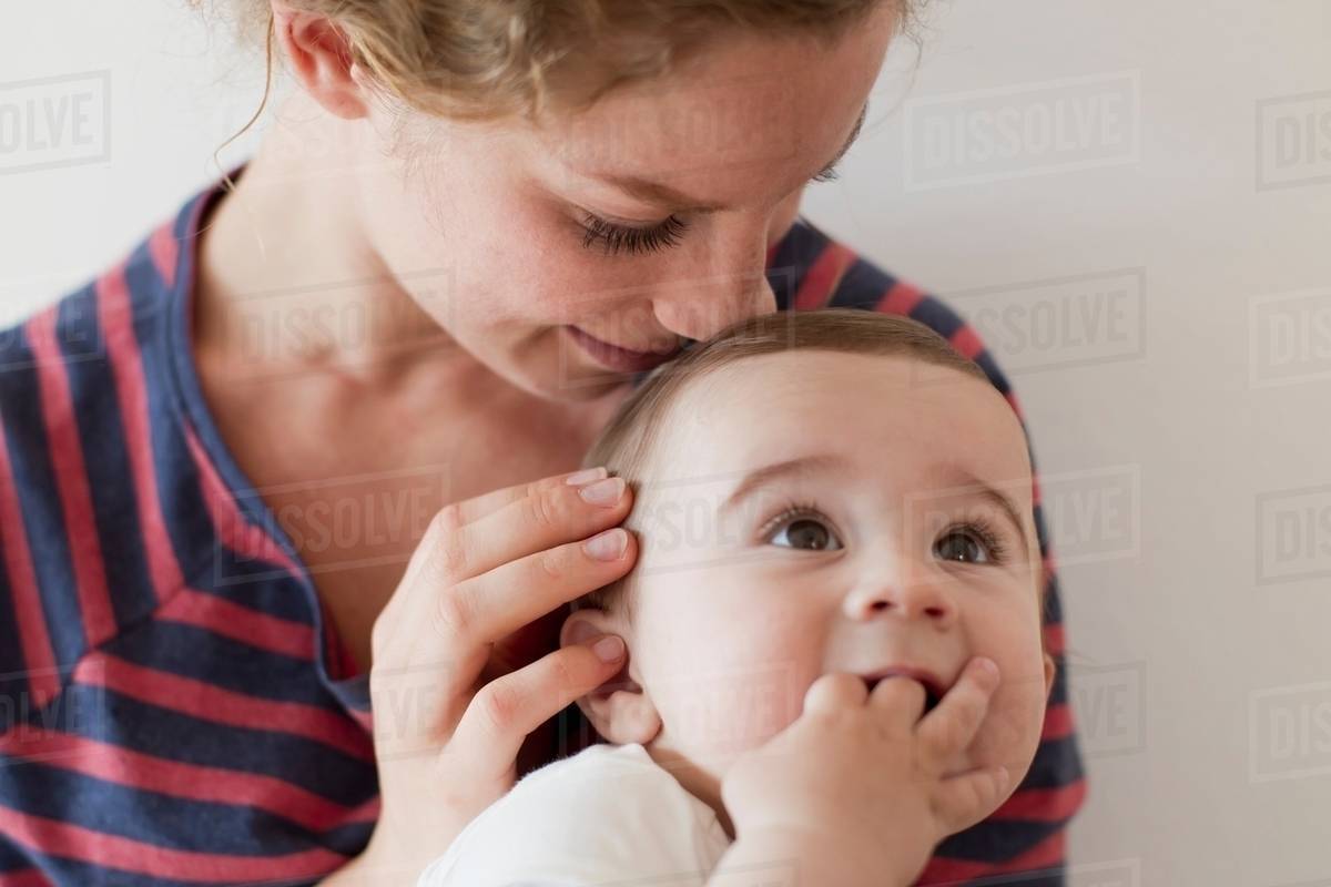 Mother nuzzling baby boy on head Stock Photo Dissolve