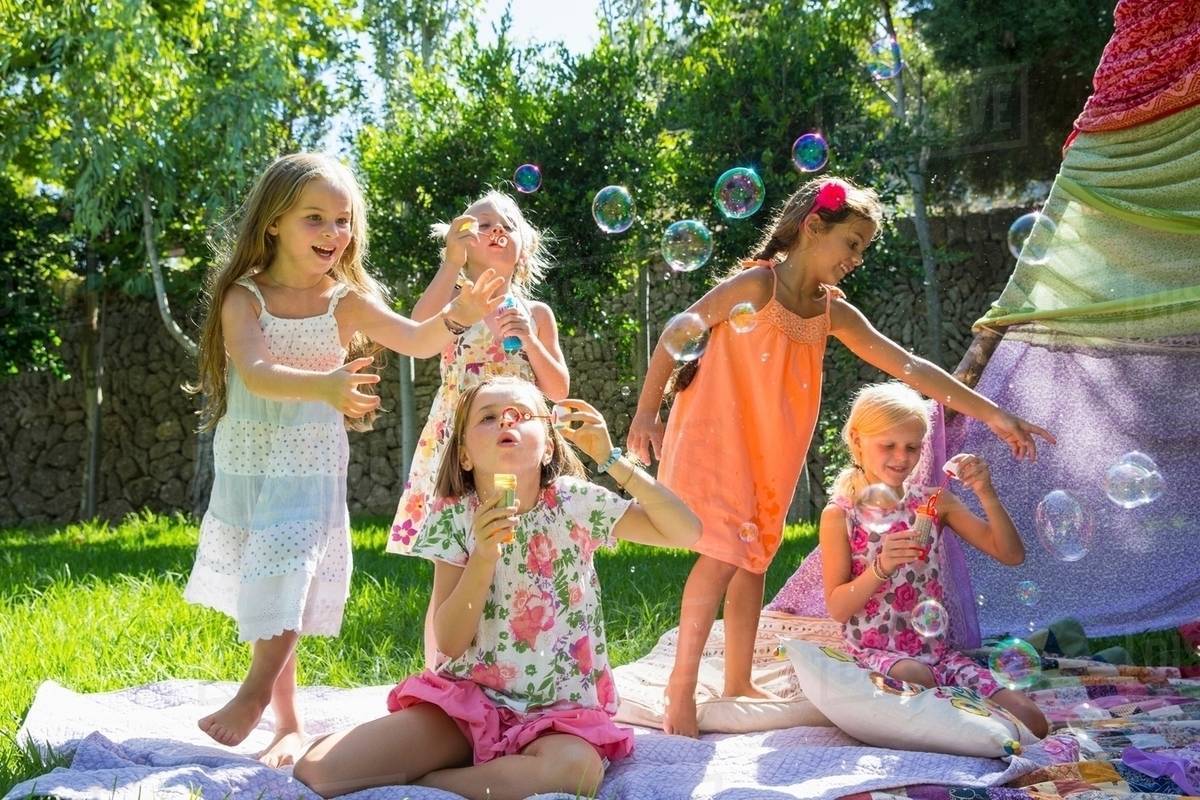 Girls blowing bubbles in summer garden party Stock Photo Dissolve