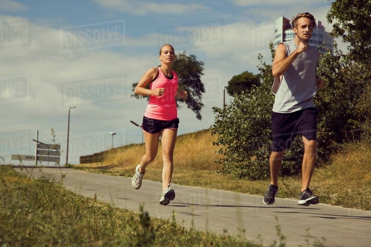 Young couple jogging down urban path Stock Photo Dissolve