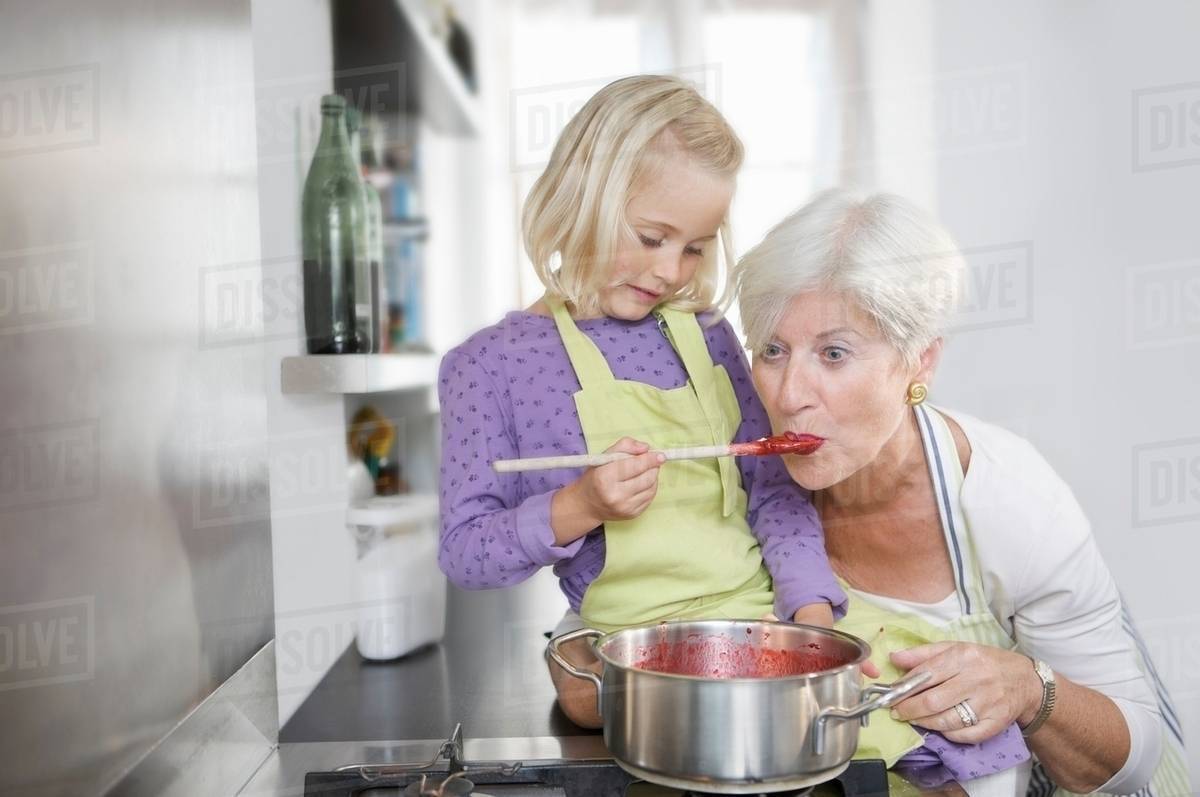 Girl with grandmother cooking jam Stock Photo Dissolve