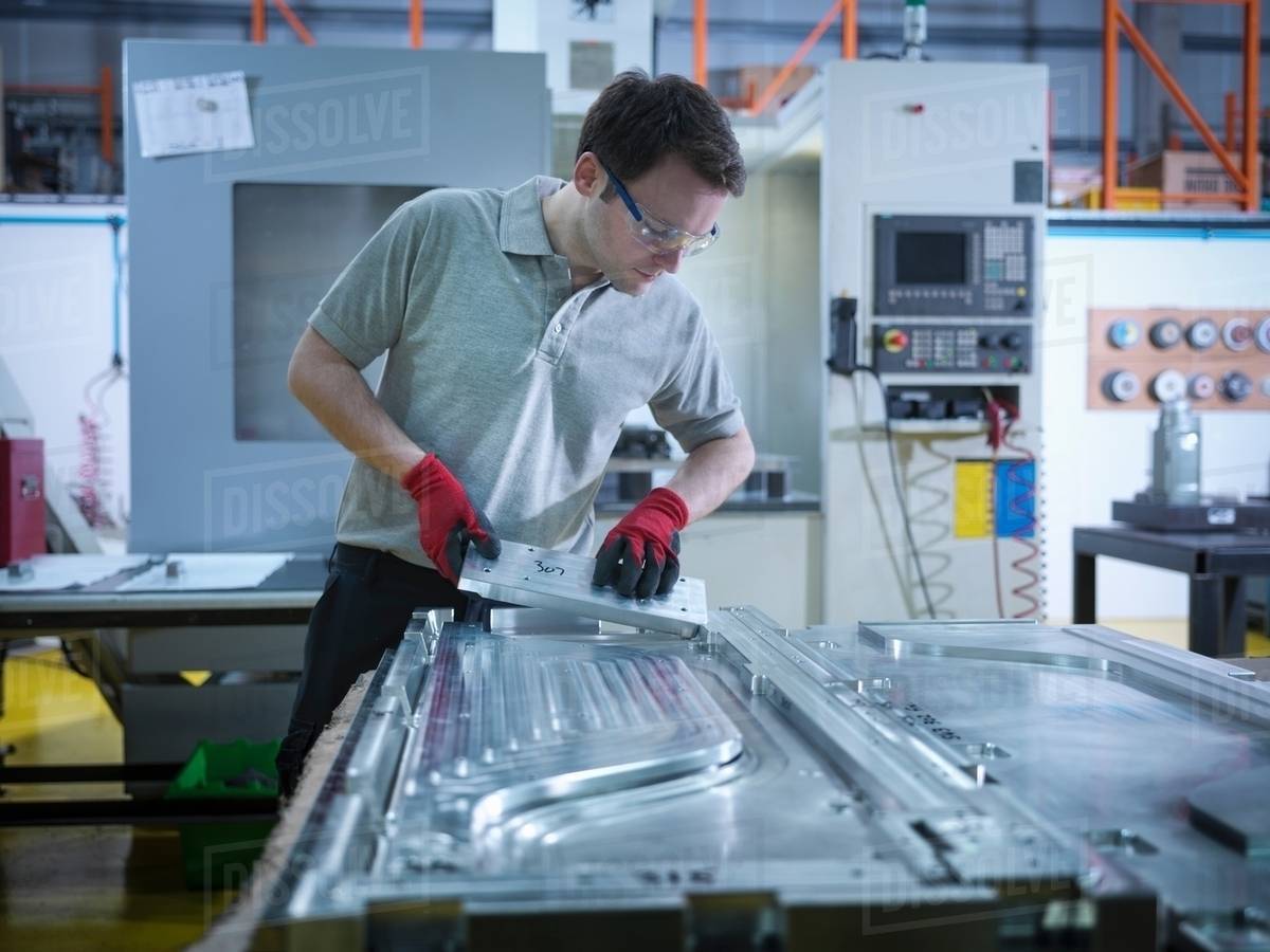 Worker inspecting part of mould in plastics factory Stock Photo