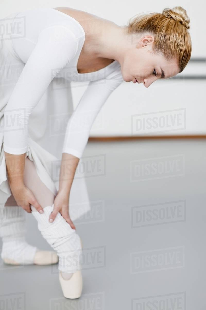 Ballet dancer examining hurt ankle Stock Photo Dissolve