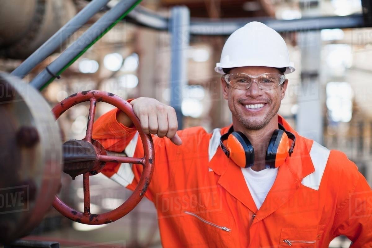 Worker smiling at oil refinery - Royalty-free Stock Photo | Dissolve