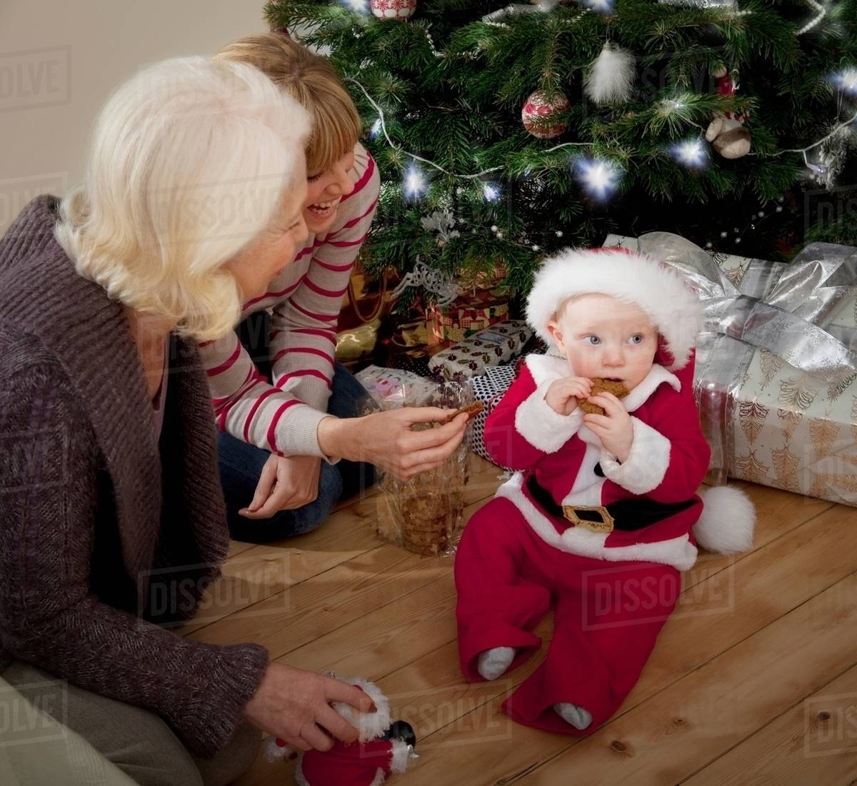 A baby dressed as Santa eating a biscuit Royalty-free stock photo