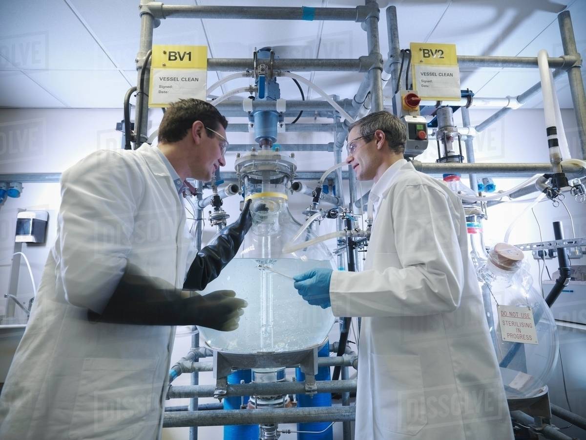 Scientists with laboratory mixing vessel - Stock Photo - Dissolve