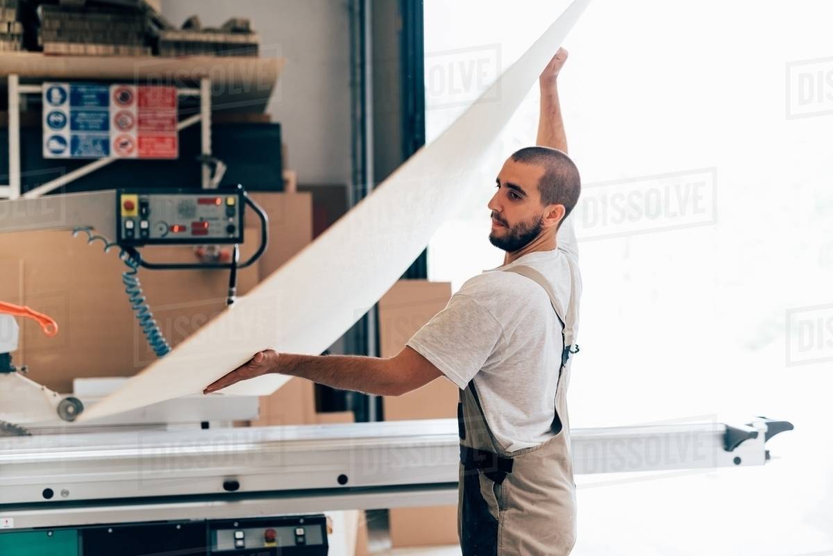 Carpenter with sheet of plywood Stock Photo Dissolve