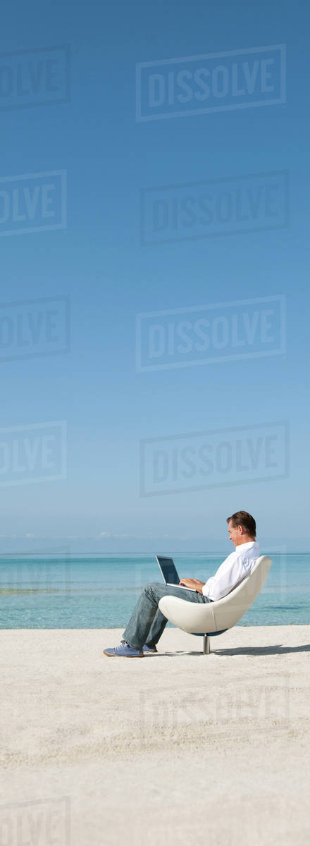 Man using laptop computer at the beach - Stock Photo - Dissolve