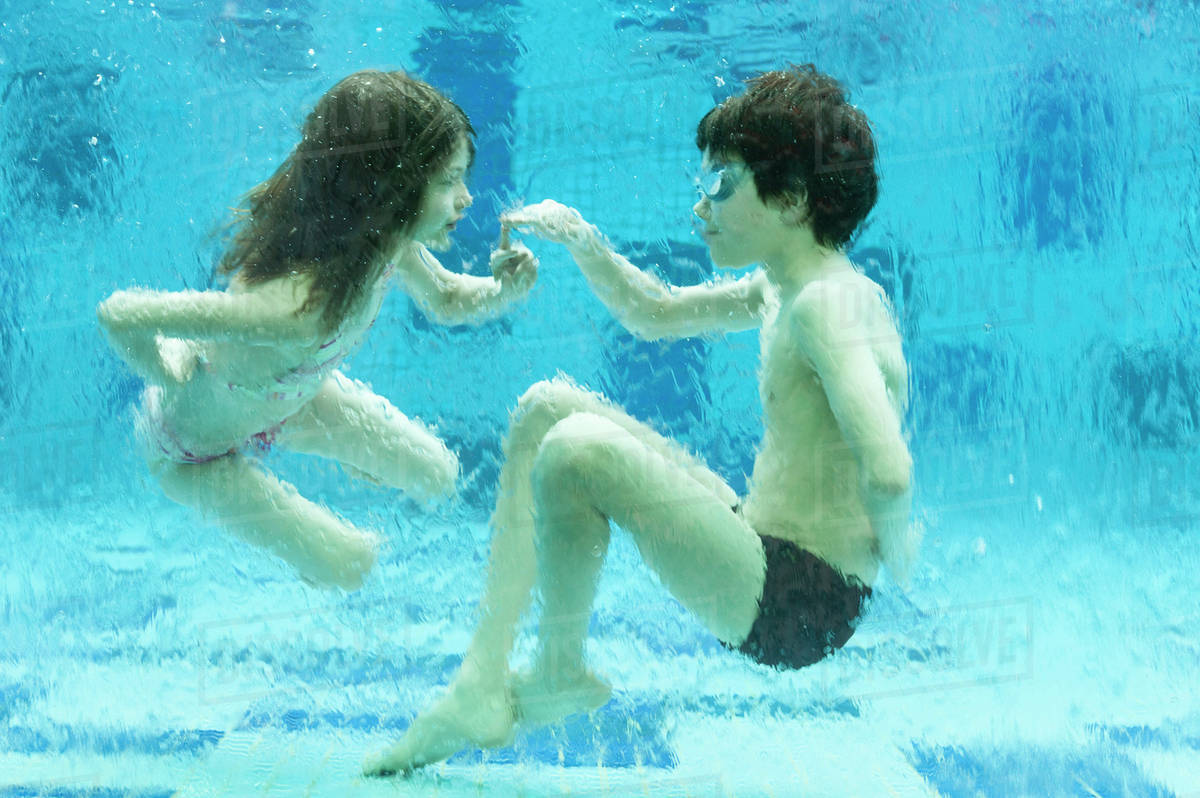 Brother and sister playing underwater in swimming pool Royalty-free stock photo