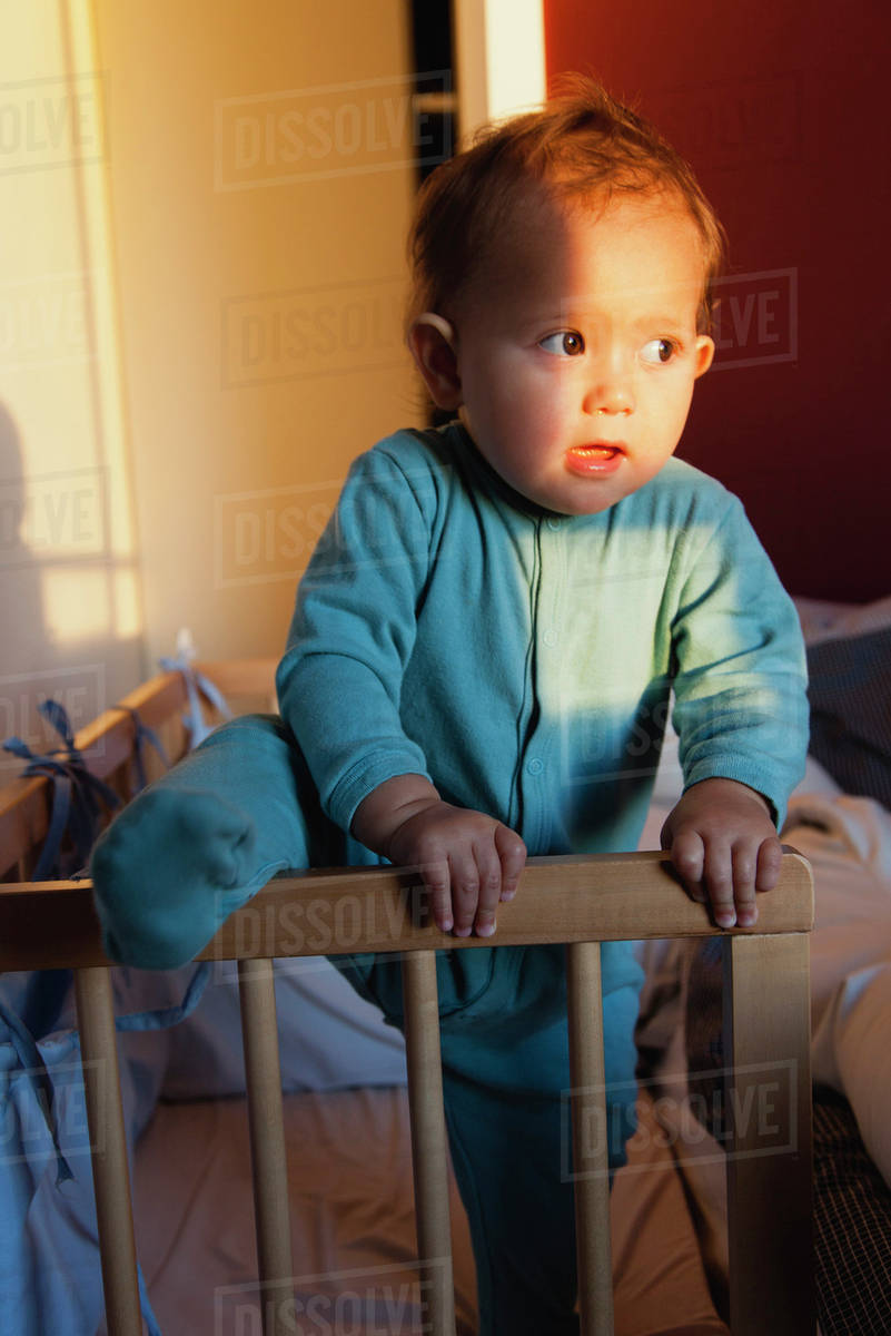 Baby girl climbing out of crib Stock Photo Dissolve