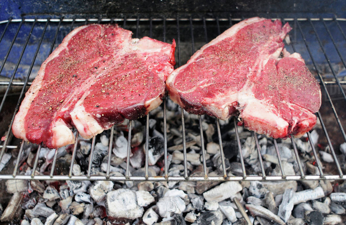 Uncooked Tbone steaks on barbecue grill Stock Photo Dissolve