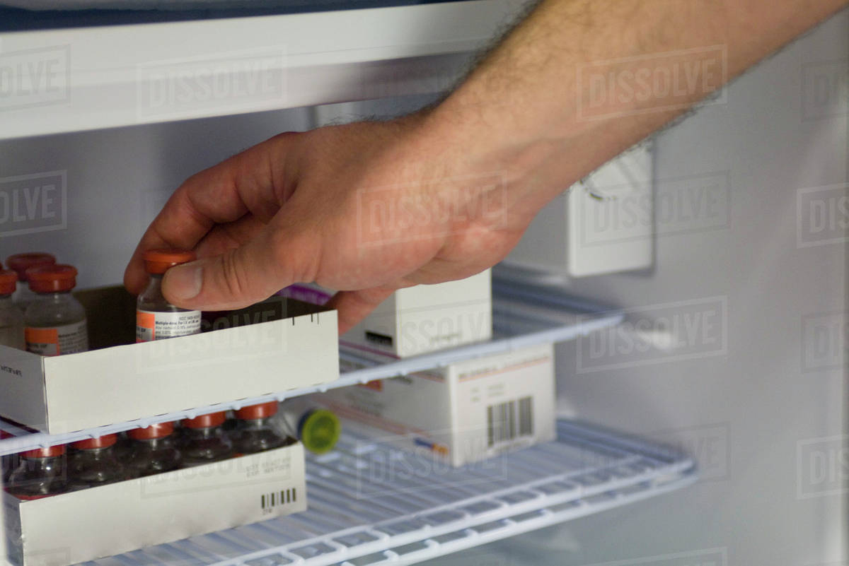 Healthcare professional removing medication vial from refrigerator