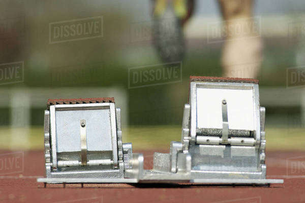 Starting blocks, runner in background - Stock Photo - Dissolve