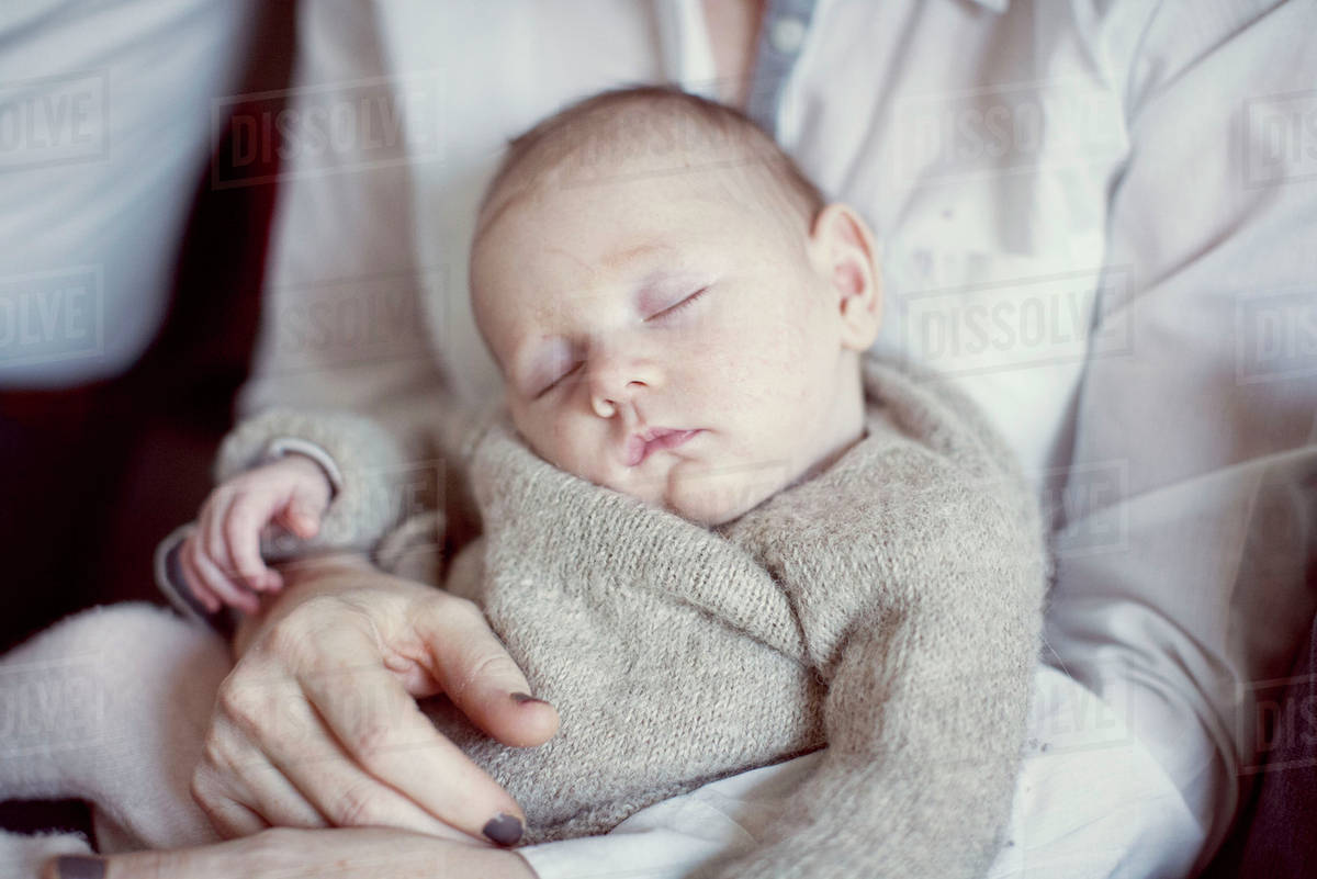 Baby sleeping on mother's lap, cropped Stock Photo Dissolve