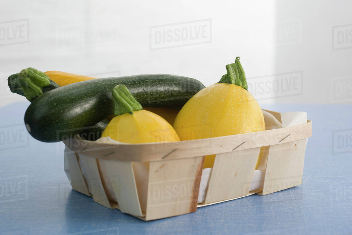 Zucchini and gold ball squash in basket Stock Photo Dissolve