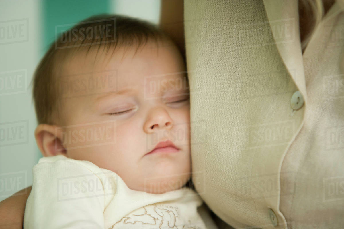 Baby sleeping against mother's chest, closeup Stock Photo Dissolve