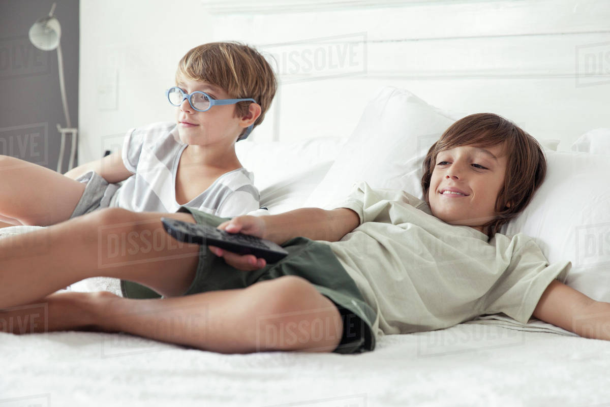 Boys watching TV on bed Stock Photo Dissolve