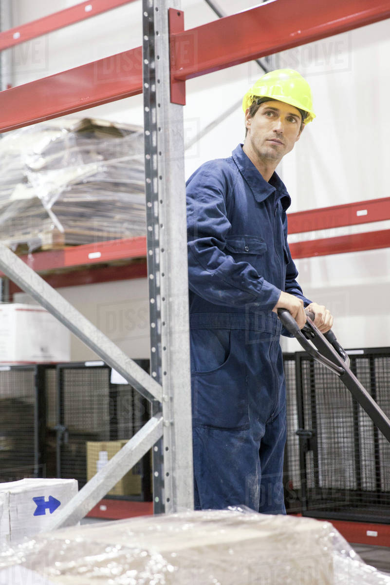 Worker operating pallet jack in warehouse Stock Photo Dissolve