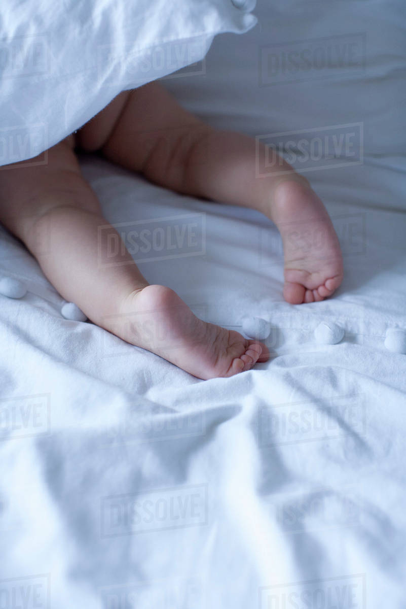 Baby's barefeet under duvet, cropped Stock Photo Dissolve