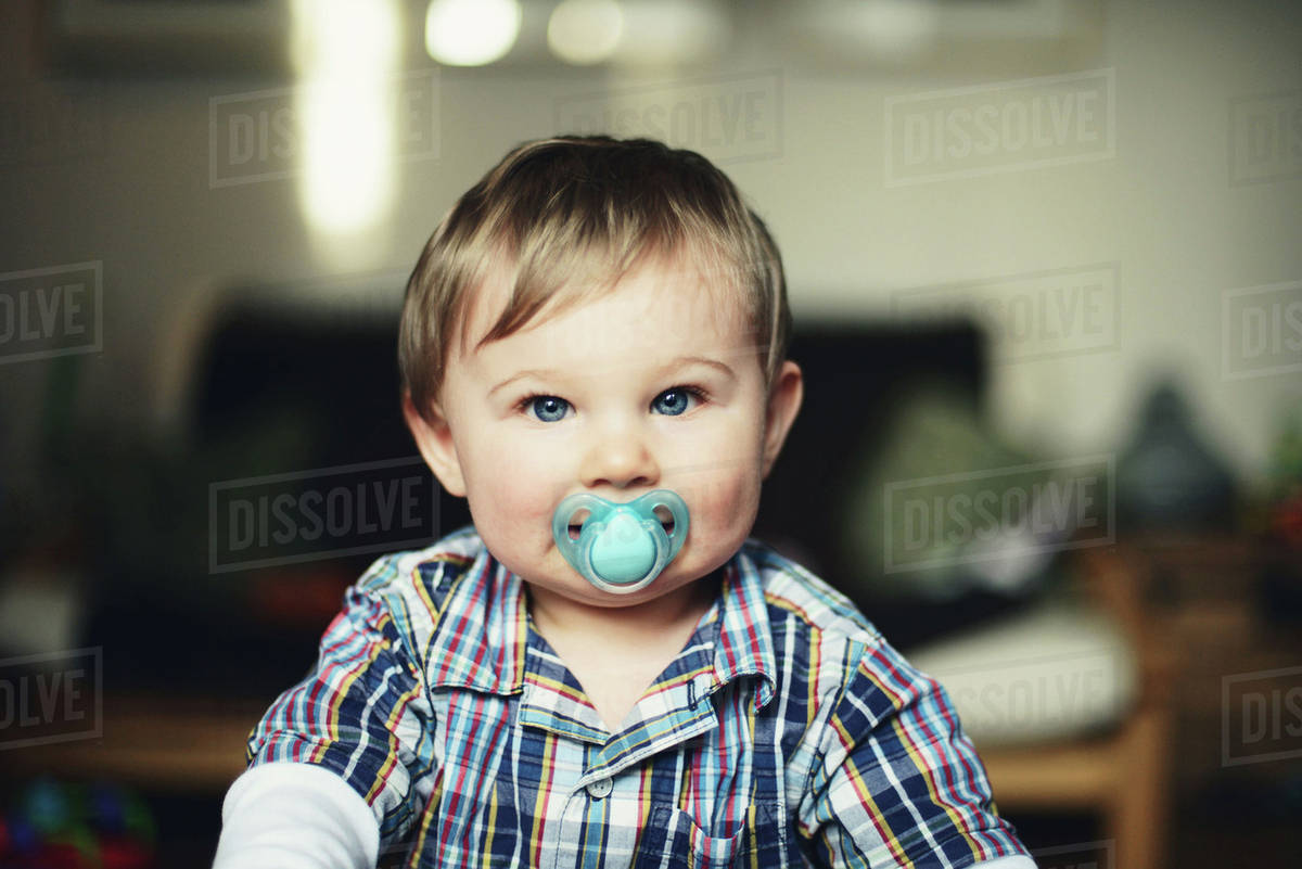 Baby boy with pacifier in his mouth, portrait Stock Photo Dissolve