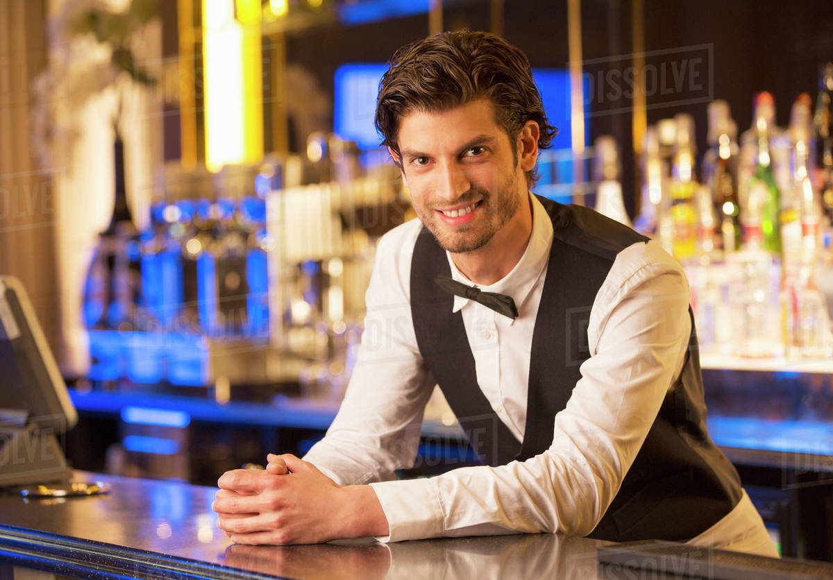 Portrait of well dressed bartender leaning on bar Stock Photo Dissolve