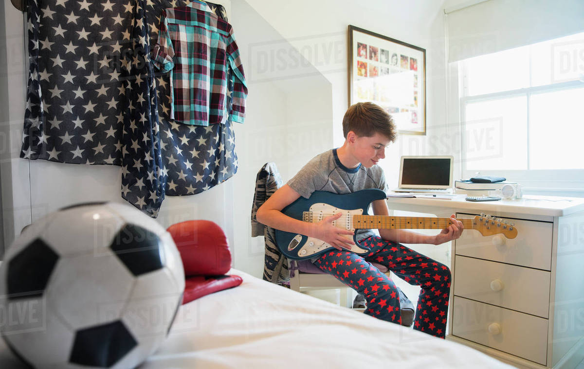 Boy playing electric guitar in bedroom Stock Photo Dissolve