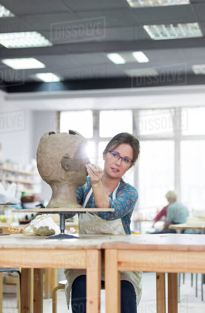 Artist sculpting face from clay in studio Stock Photo Dissolve
