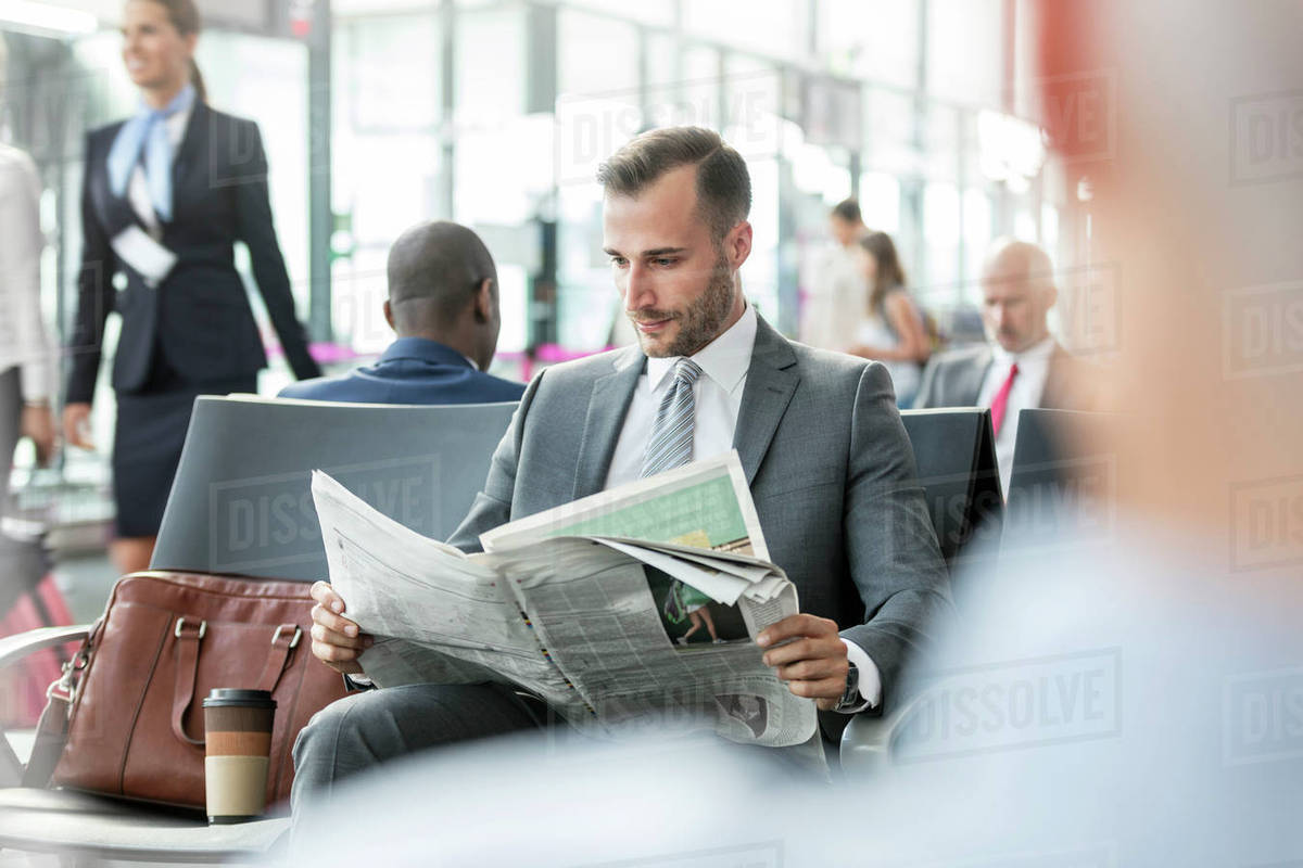 Businessman reading newspaper in airport departure area Royalty-free stock photo