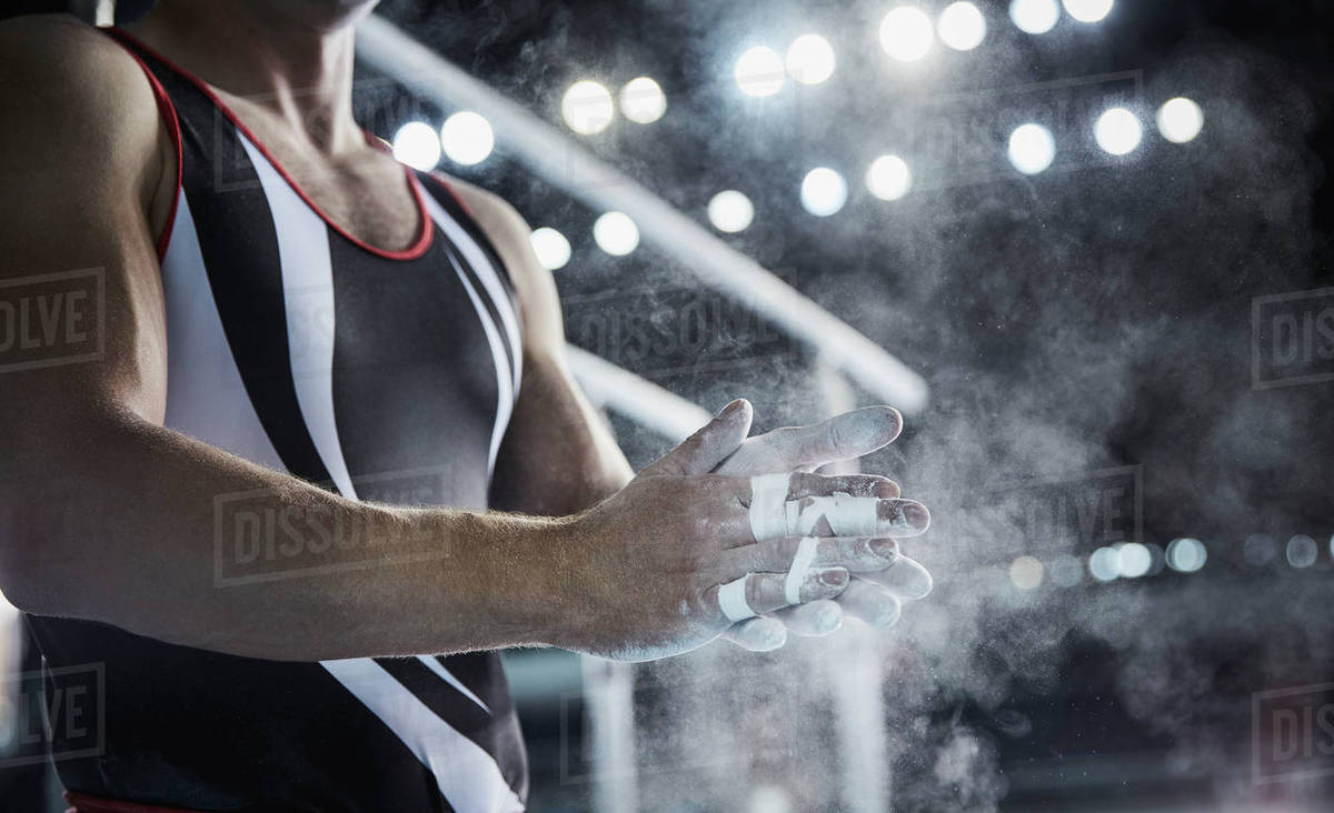 Male gymnast rubbing chalk powder on hands below parallel bars Stock Photo Dissolve