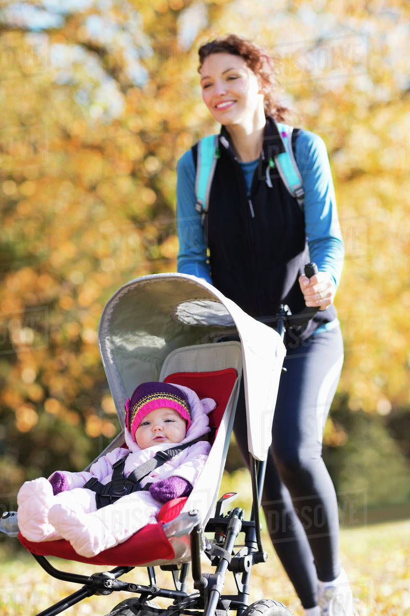 Woman running with baby stroller in park Stock Photo Dissolve