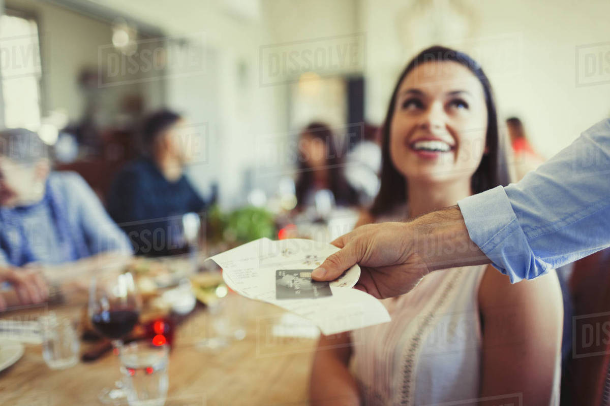 Waiter returning bill and credit card to woman dining at restaurant table Stock Photo Dissolve