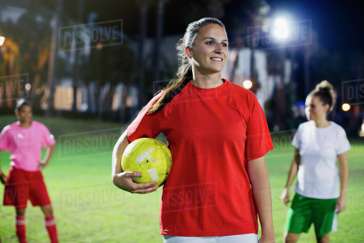 Portrait confident, smiling young female soccer player on field at