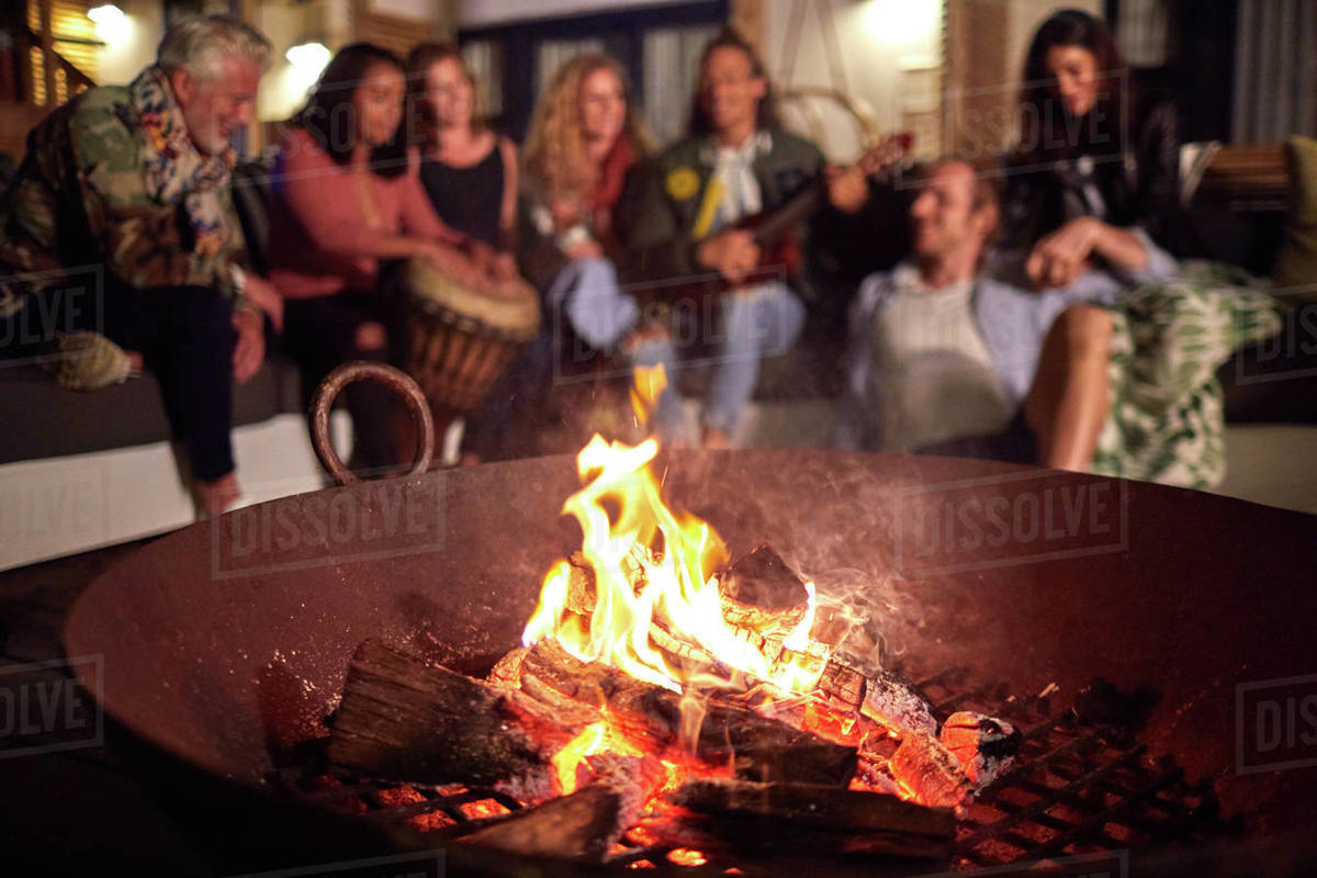 Friends hanging out, playing music on patio next to fire pit Royalty-free stock photo