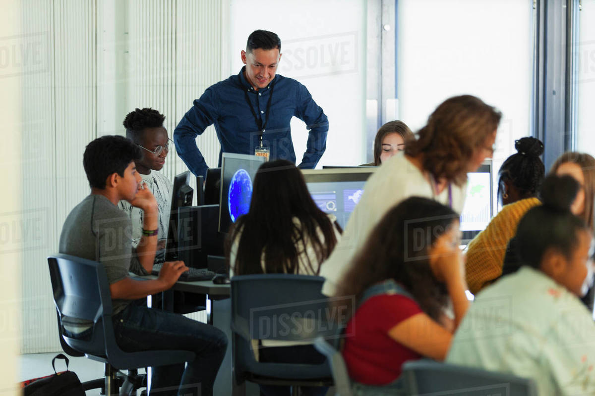 Junior high students and teacher using computers in computer lab ...