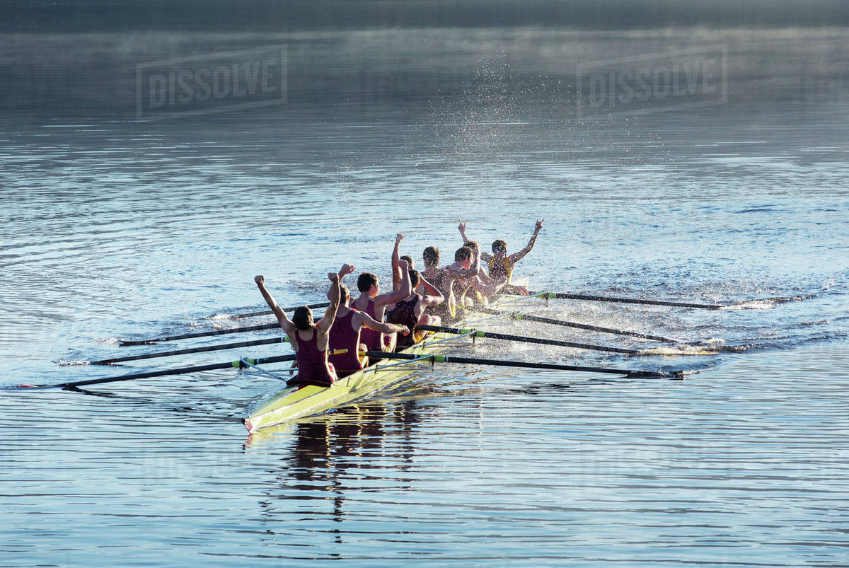 Rowing team celebrating in scull on lake Stock Photo Dissolve