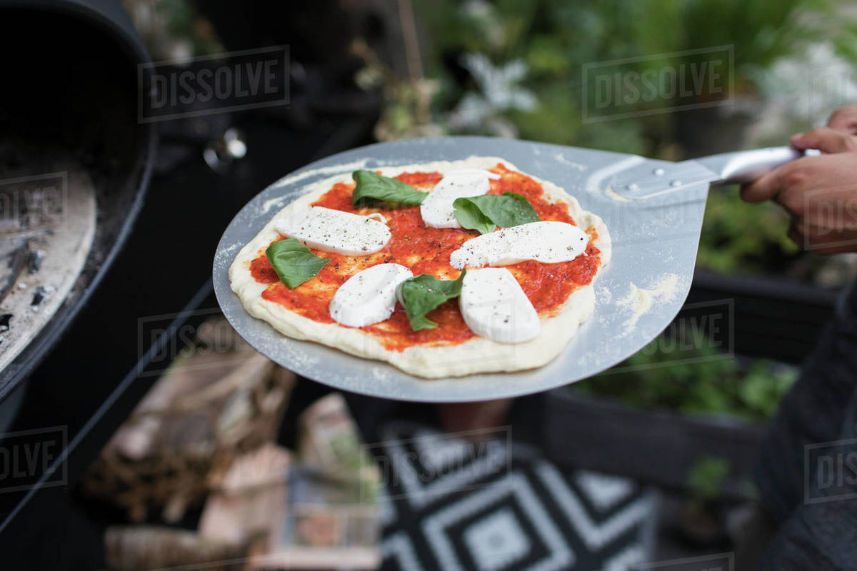 Fresh homemade pizza on pizza peel at oven Stock Photo Dissolve