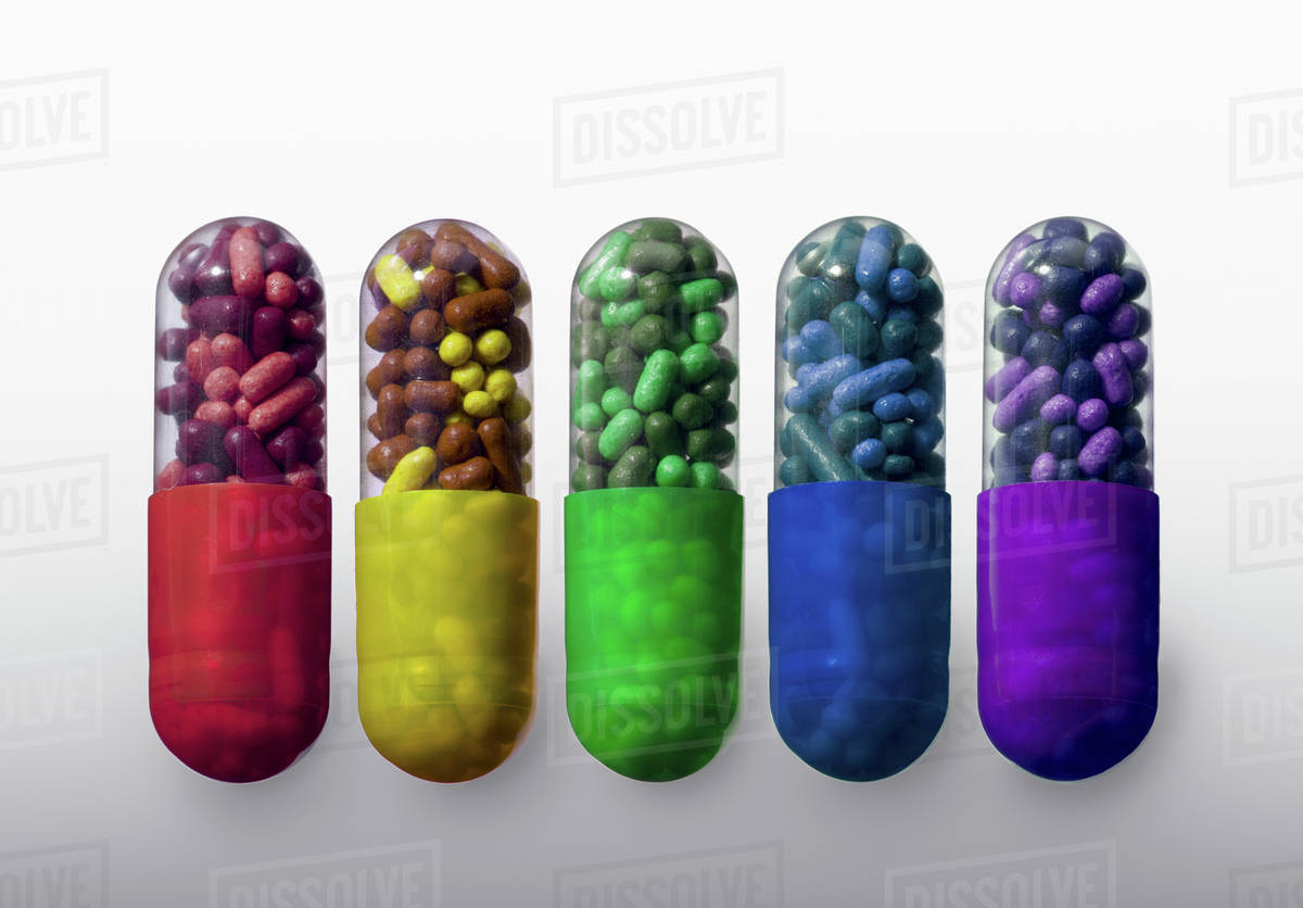 A row of vibrantly variously colored capsule pills, closeup Stock