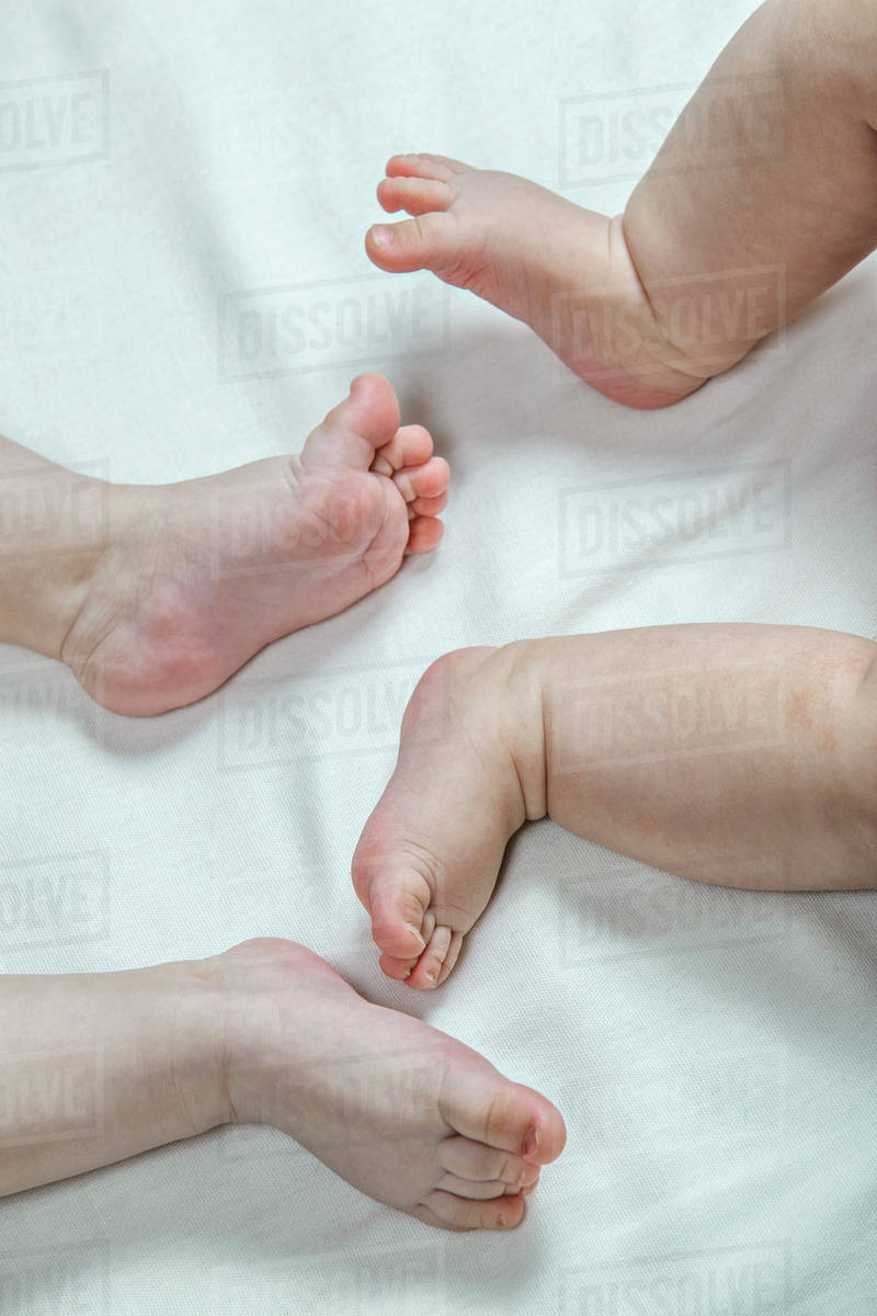 Two barefoot babies lying down, closeup of feet Stock Photo Dissolve