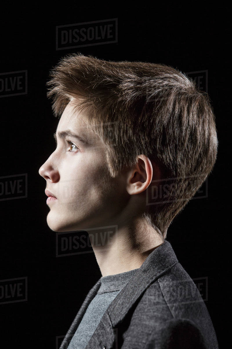 Profile shot of teenage boy over black background Stock