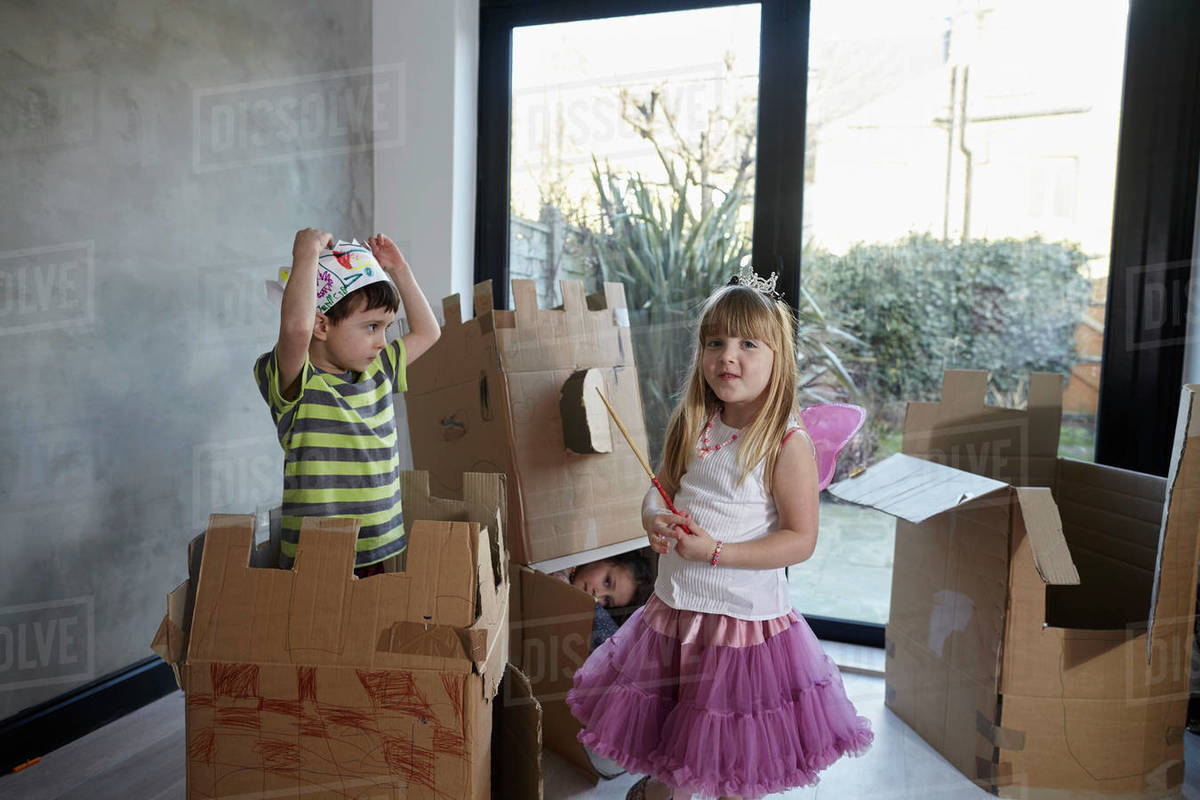 Children wearing costume playing with cardboard boxes against window Royalty-free stock photo