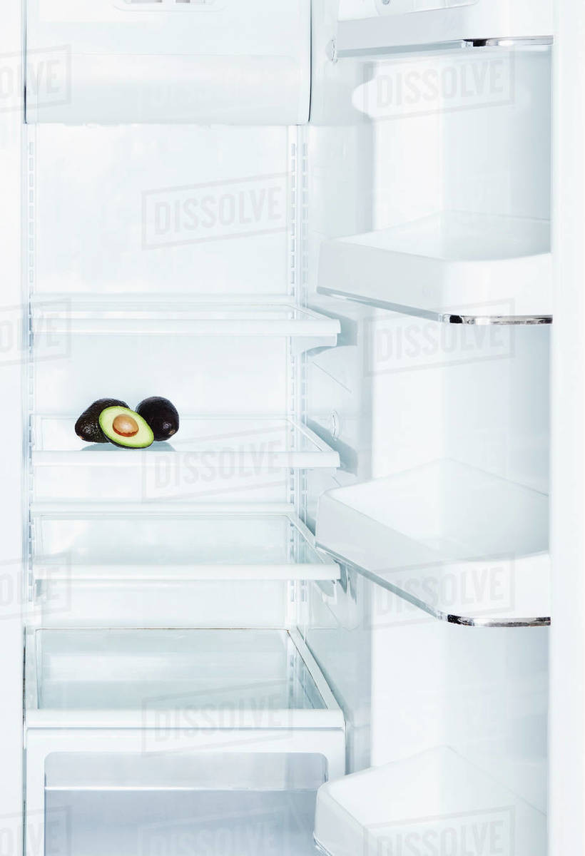 Avocados in open, empty white refrigerator Stock Photo Dissolve