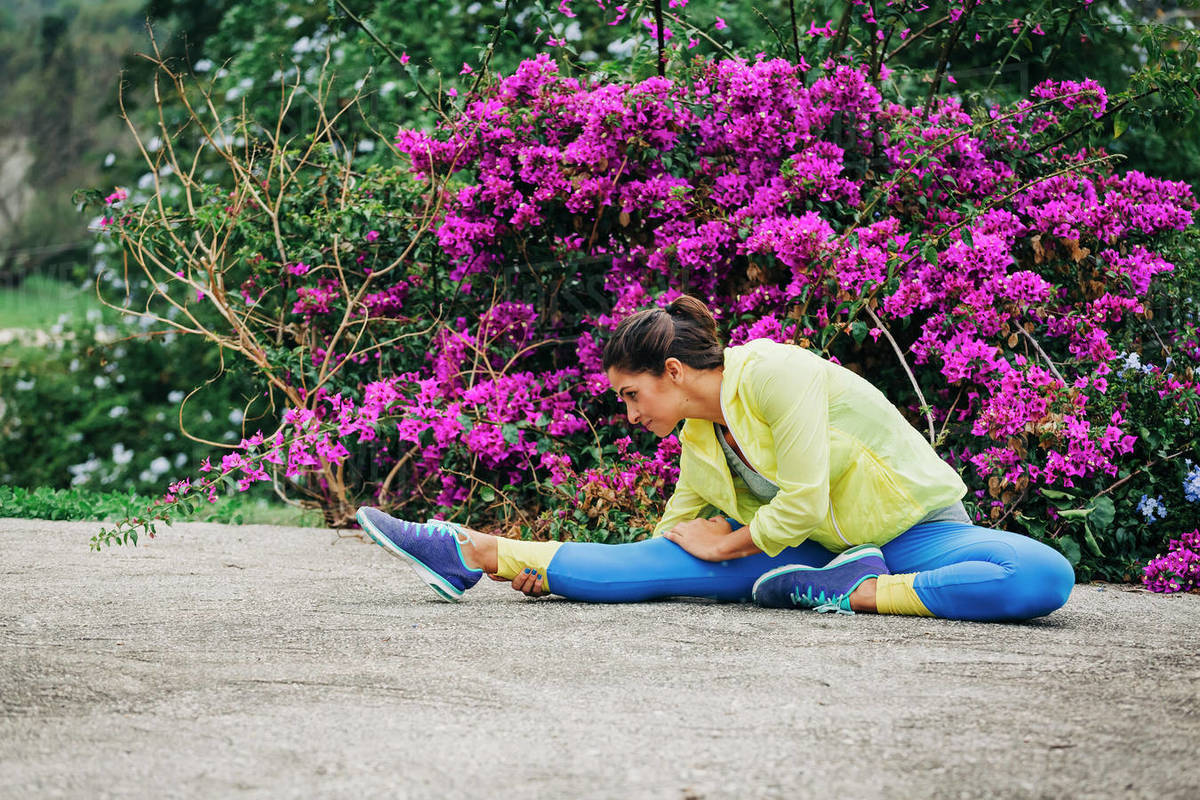Fit female personal trainer exercising, stretching in park Royalty-free stock photo