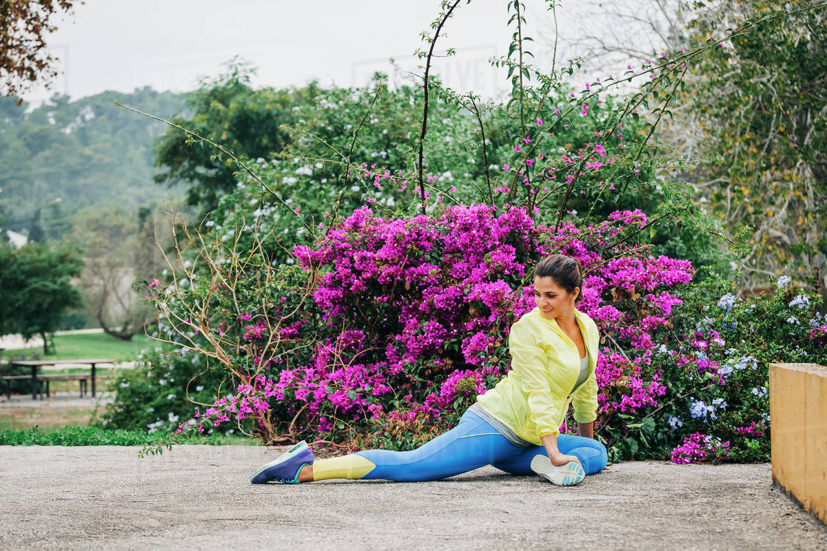 Fit female personal trainer exercising, stretching in park Royalty-free stock photo