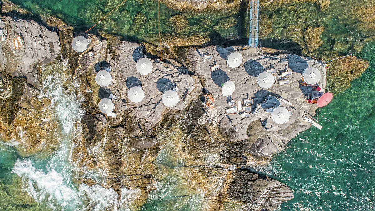 Aerial view from above beach umbrellas on sunny rocks above ocean, Nervi, Italy Royalty-free stock photo