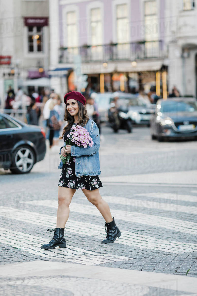 Portrait smiling young woman crossing street with flower bouquet Royalty-free stock photo