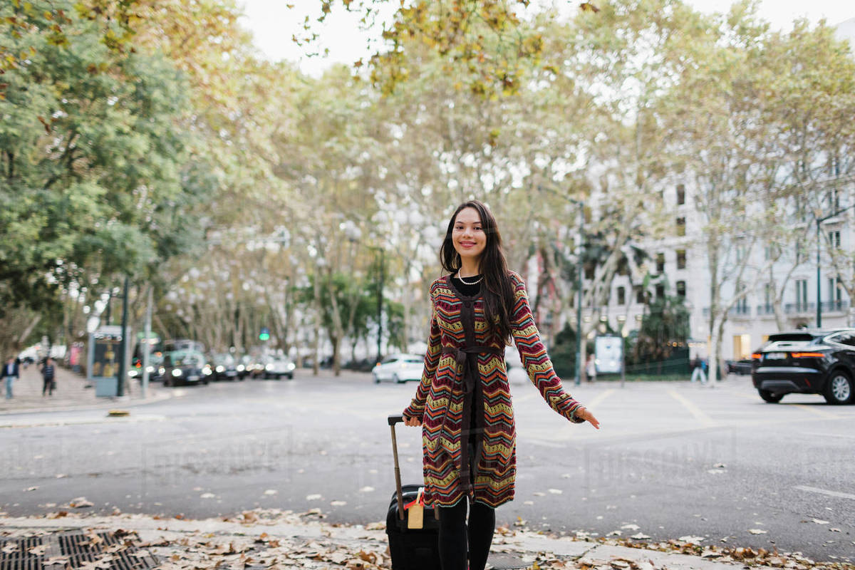 Portrait happy female tourist with suitcase on urban autumn street Royalty-free stock photo