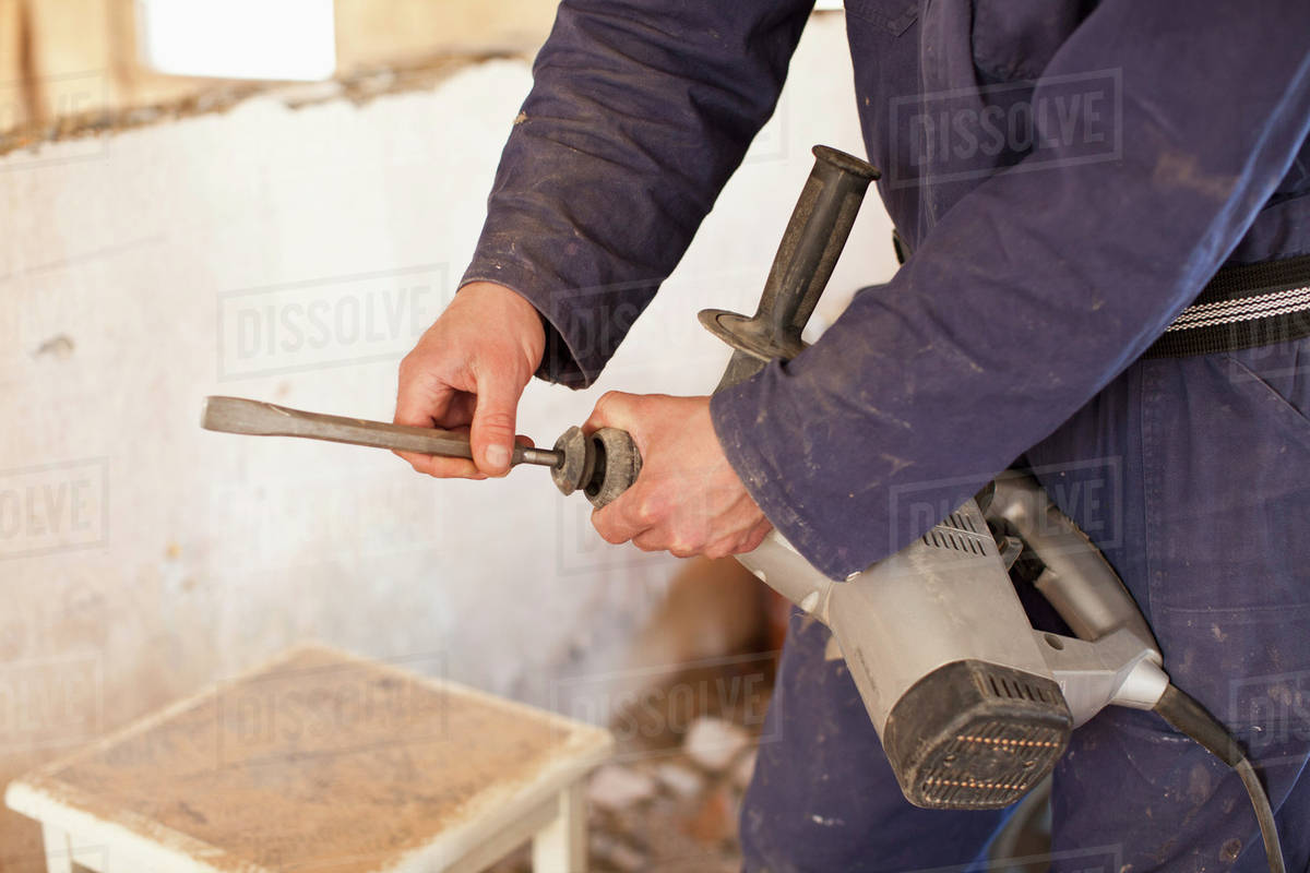 A manual worker attaching a drill bit to a drill Stock Photo Dissolve